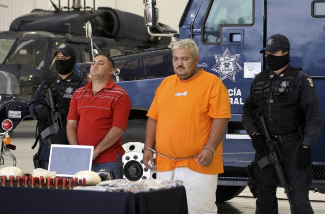 Mexican federal police stand guard beside two of 33 suspected drug-trafficking gang members who were arrested this month during Mass at a Catholic church in Michoacan.