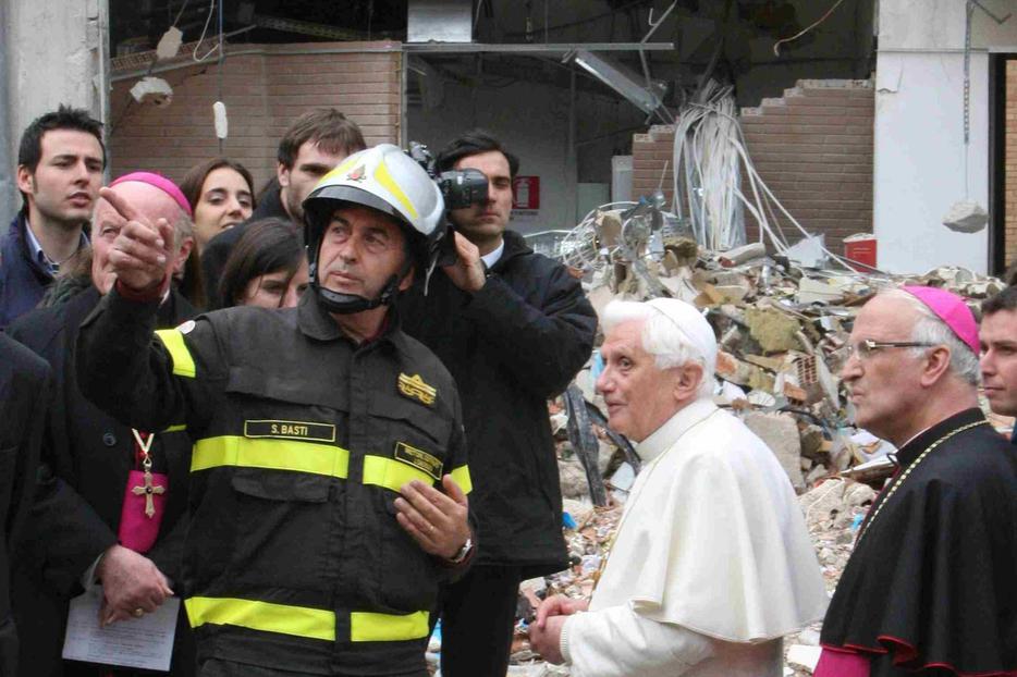 Pope Benedict XVI talks with a firefighter as he visits a collapsed dorm at the University of L'Aquila in L'Aquila, Italy.