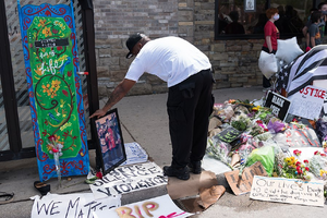 A man leaves a photograph at a memorial for George Floyd on May 27 in Minneapolis. 