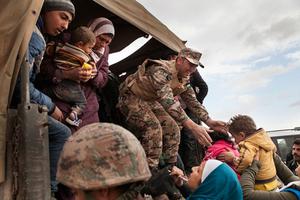 Jordanian troops and U.N. members help bring refugees to the Zaatari refugee camp.