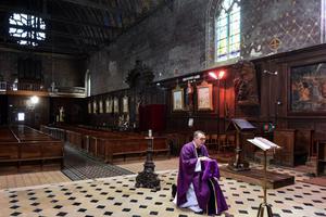 French priest Olivier Monnier broadcasts a Mass with a video chat application running on his smart phone fixed on a wooden candlestick facing the altar on April 3, 2020 at the empty Saint-Jacques church in Illiers-Combray, France.