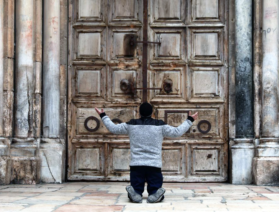 A man kneels in prayer in front of the closed doors of the Church of the Holy Sepulcher in Jerusalem April 9, during the COVID-19 pandemic lockdown.