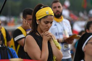 A pilgrim prays during the opening Mass of World Youth Day in Krakow, Poland, July 26, 2016.