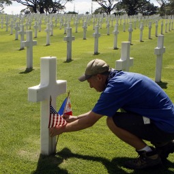 A man places Philippine and U.S. flags on the grave of an unknown soldier after a Veterans Day memorial ceremony at an American cemetery in Manila, Philippines. The cemetery contains the remains of 16,631 Americans who died in the Pacific, China, India and Burma during World War II.