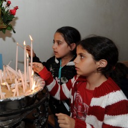 HOPE FOR A BRIGHTER FUTURE. Palestinian girls light candles in front of an icon at St. Joseph Church in the West Bank town of Jifna May 7. 
