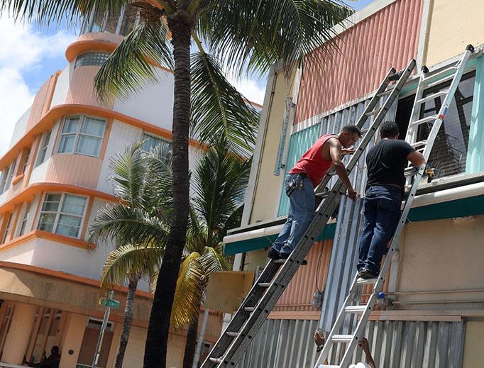 Workers place hurricane shutters over windows of a building as they prepare for the arrival of Hurricane Irma on September 8, 2017 in Miami Beach, Florida. Florida appears to be in the path of the Hurricane which may come ashore at category 4.