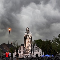 Our Lady of the New Millennium statue stands tall outside St. John the Evangelist Church as dark storm clouds roll through St. John, Ind., May 22. The 33-foot-tall stainless-steel statue of Mary found a permanent home at the church after being carted from parish to parish around the Chicago area for more than a decade. A dedication service planned for the outdoors had to be moved inside because of the weather. 
