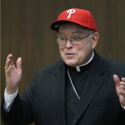 Archbishop Charles Chaput dons a Phillies hat at the July 19 press conference announcing his new appointment.