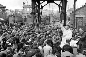 Father (Major) Edward J. Waters, a U.S. Army chaplain from Oswego, New York, blesses U.S. military personnel in Weymouth, England, on June 6, 1944.