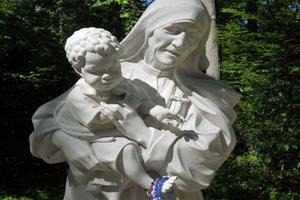 Above, the Mother Teresa of Calcutta Grotto will be dedicated on Sept. 10. Pilgrims often drape rosaries on this statue and others at the shrine. These sacramentals are eventually sent to the missions. Below, Father Harry Brown stands outside of Our Lady of Guadalupe Grotto. After Masses, processions and prayers, joyful pilgrims in costume fill the plaza with singing and folk dancing. Our Lady of Grace Shrine features a statue of Filipino martyr San Lorenzo Ruiz. And a crucifix was erected in memory of people killed in World War I.  

