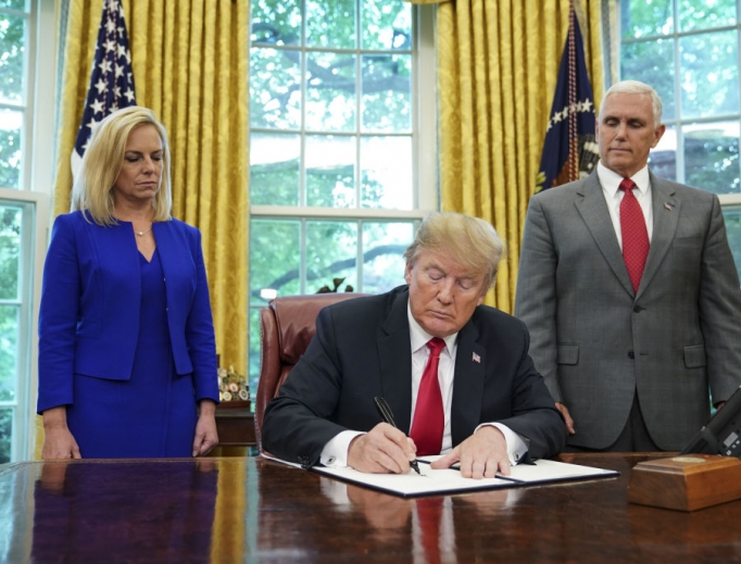 Watched by Homeland Security Secretary Kirstjen Nielsen (l) and Vice President Mike Pence, U.S. President Donald Trump signs an executive order on immigration in the Oval Office of the White House June 20. The order is aimed at putting an end to the controversial separation of migrant families at the border. 'It's about keeping families together,' Trump said at the signing ceremony. 'I did not like the sight of families being separated,' he added. 