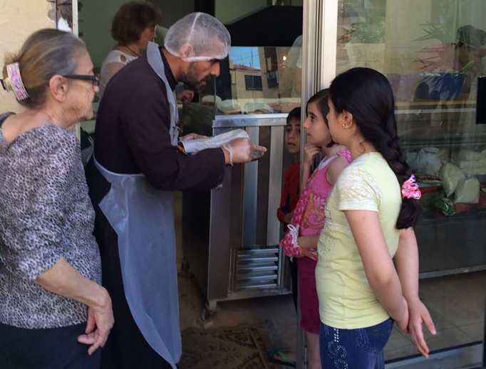 Above, Father Majdi Allawi, founder of Lebanese Charity Bonheur du Ciel ("Heaven's Joy"), greets children at the organization's free bakery for the poor.
Below: Father Allawi prays in the chapel at the organization's free supermarket for the poor and sweeps the floor at the organization's free salon for the poor.