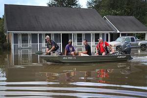 Richard Schafer navigates a boat past a flooded home on Aug. 15 in Baton Rouge, La. Record-breaking rains pelted Louisiana over the weekend, leaving the city with historic levels of flooding that have caused at least seven deaths and damaged thousands of homes. 
