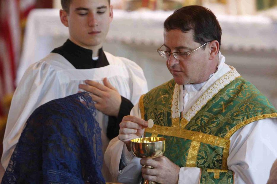 Father Kevin Robinson distributes Communion at St. Michael the Archangel Chapel in Farmingville, N.Y., in early February. The chapel is affiliated with the Society of St. Pius X.