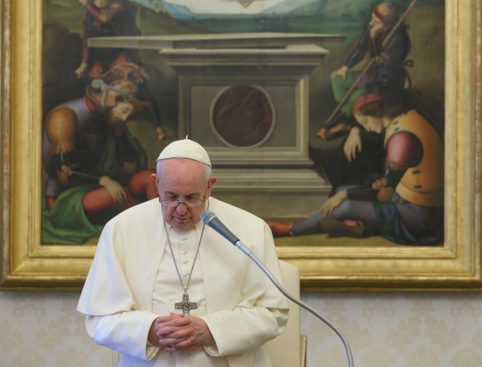 Pope Francis bows his head in prayer during his weekly General Audience from the Apostolic Palace. 