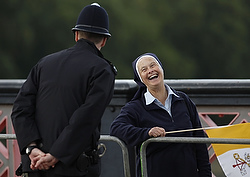 A nun laughs as she chats with a police officer while she waits to see Pope Benedict XVI's popemobile cross Lambeth Bridge in central London Sept. 17.