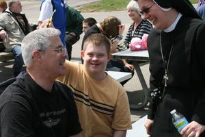 COMPASSIONATE MISSION. Above, Sister Brenda McHugh; St. Louis Center resident, 19-year-old Tony Cossentino, who loves basketball; and Rick Visel, a supervisor at St. Louis Center, enjoy themselves during a fundraiser. 
LOVING CARE. Below, Father Fortunato Turati greets Kateri, whose parents and grandparents bring her regularly to daily Masses at the Pious Union of St. Joseph. She received her first holy Communion from the priest on the day of the canonization of St. Kateri Tekakwitha, October 21, 2012.
And Sister Margaret Mary Schissler, with Tia, Rita, Bob and Nancy the nurse (slightly hidden), playing Pokeno at the adult center at Sacred Heart Church in East Providence, R.I. 