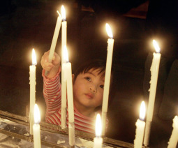 Two-year-old Catherine Louise Niiniaro lights a candle in the parish of St. Maria in Helsinki.
