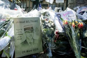 Flowers and a portrait lay at the gate of Lt. Col. Arnaud Beltrame's barracks in Carcassonne, France, March 29. French officials attended the funerals in southern France for the four victims of last week's extremist gun rampage. On Wednesday, France held a national homage to Beltrame, who was given a posthumous Legion of Honor for his heroism in swapping himself for a hostage and potentially preventing further killings. 