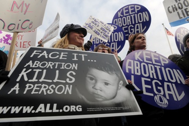 Maria Burud, left, of Madison, Wis., holds a pro-life sign next to demonstrators for legal abortion at the Jan. 22 March for Life outside the Supreme Court building in Washington.
