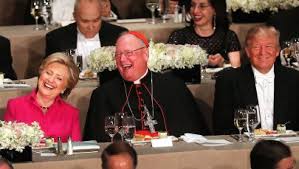 Cardinal Dolan of New York sits between Hillary Clinton and Donald Trump