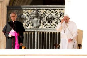 Pope Francis prays, making the Sign of the Cross, at the end of his general audience March 14. 