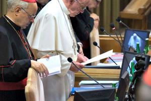 Pope Francis leads prayer inside the hall of the Synod of Bishops.
