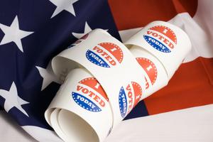 Voting stickers spiral against an American flag.