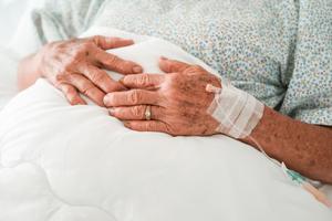 An elderly woman sits in a hospital bed.