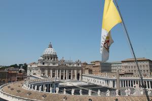 The flag of Vatican City with St. Peter's Basilica in the background. This particular flag with vertical bands of gold and white with the coat of arms of the Holy See was adopted on June 7, 1929.
