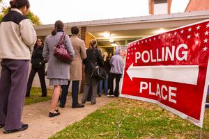 Voting polling place sign and people lined up on presidential election day.