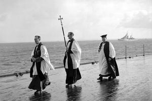 The Chaplain of the Fleet (L) and the Archbishop of Canterbury, William Temple (R) process with a crucifer for an Anglican service on the quarterdeck of HMS King George V at Scapa Flow, in the Orkney Islands, Scotland, during World War II. After the war, both institutions would undergo a steep decline in prestige and power, with the Royal Navy dropping from more than 2,000 ships to fewer than 80 operational commissioned ships in 2020, and Anglican churchgoing currently hovering around 1% of the U.K. population.