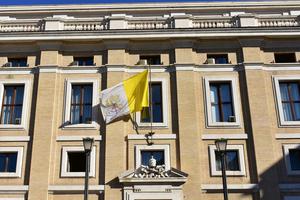 Building with the flag of the Vatican and the Vatican Coat of Arms in Vatican City.