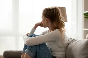 A young woman sits looking out the window contemplating an abortion.
