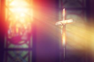 Rays of light from a stained glass window shine down on a crucifix inside a Catholic church.