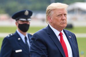 President Donald Trump walks  with Air Force Major General John P. Healy in the background wearing a face mask at Dobbins Air Reserve Base.