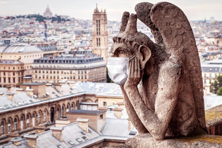 Gargoyle sits atop Notre Dame in Paris wearing a face mask.