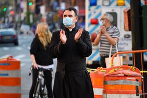 A priest applauds to show his gratitude to medical staff and essential workers on the front lines of the coronavirus pandemic outside Lenox Health Greenwich Village on May 15, 2020 in New York City. A priest applauds to show his gratitude to medical staff and essential workers on the front lines of the coronavirus pandemic outside Lenox Health Greenwich Village on May 15, 2020 in New York City.