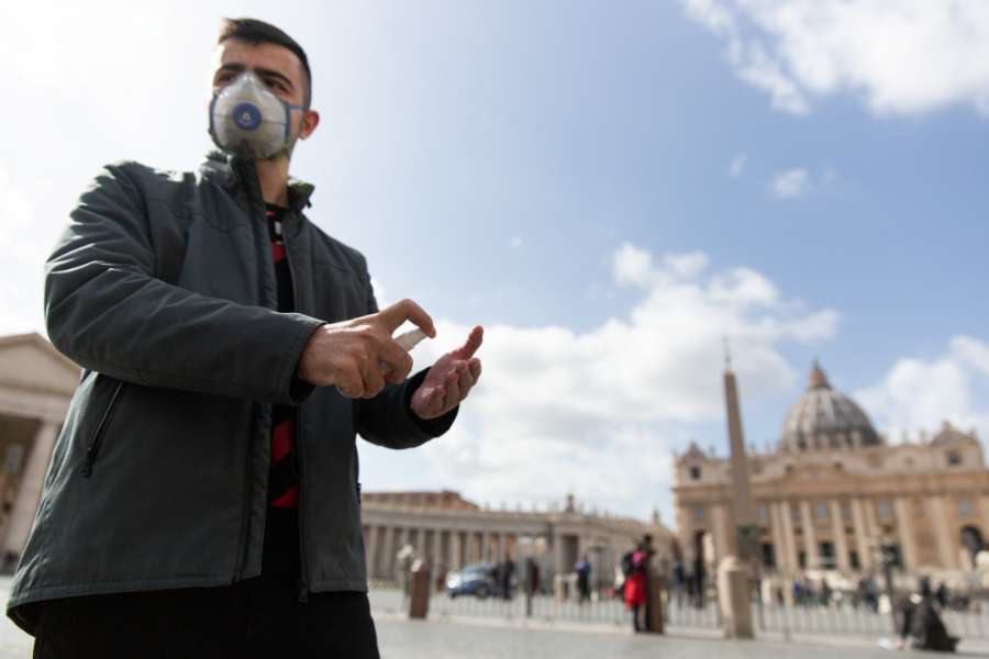 A pilgrim from Russia wears a mask and uses hand sanitizer in front of St. Peter's Basilica at the Vatican March 6, 2020.