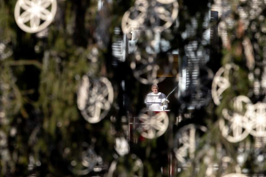 Pope Francis, seen through the Vatican’s Christmas tree, delivers an Angelus address.