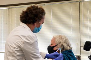Pharmacist Serena Burgdorf administers a Covid-19 Moderna vaccine shot to Christine Griffin, Army Veteran, who has a spinal injury and is inpatient at the West Roxbury VA Medical Center in Boston, MA on December 23, 2020. The VA is vaccinating front line workers and at risk patients during phase one.