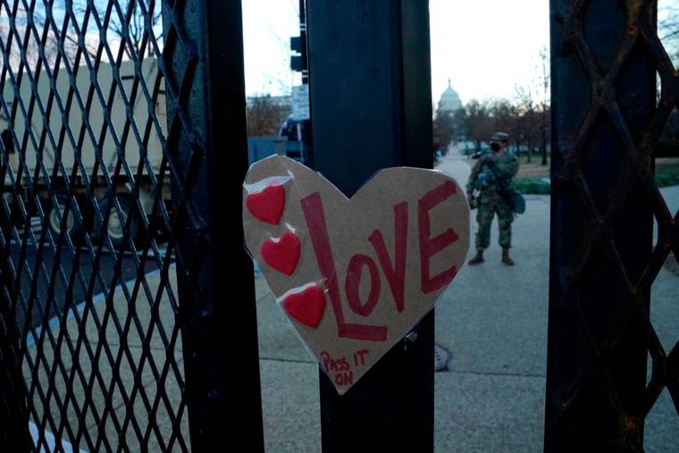 A sign reading "Love" is placed on a barrier outside the US Capitol as National Guard troops stand guard ahead of the inauguration ceremonies for President-elect Joe Biden and Vice President-elect Kamala Harris on January 18, 2021 in Washington, DC.