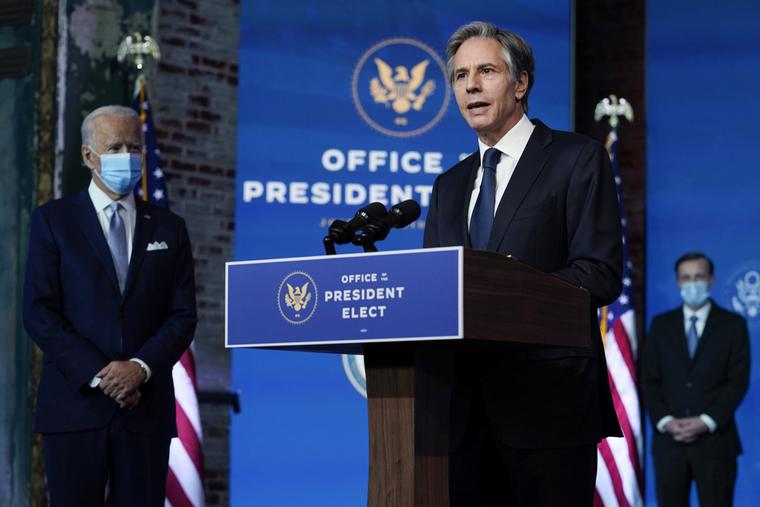 Secretary of State Antony Blinken with President-elect Joe Biden in the background.