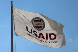 US AID Agency for International Development flag with emblem seal outside headquarters building.