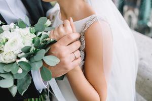 Groom holds bride's wrist on their wedding day.
