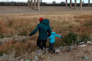 A Guatemalan migrant and his son cross the Rio Grande natural border between El Paso, state of Texas, US, and Ciudad Juarez, Chihuahua state, Mexico in search of political asylum on January 26, 2021.