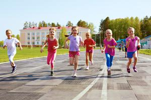 Young girls run outside on the track.