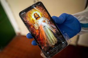Father Martin Miskuf  shows his mobile phone wrapped in plastic to a COVID patient hospitalized at University Hospital J.A. Reiman in Presov, Slovakia on February 18, 2021.  In a hospital with broken windows and peeling paint in a poor part of Slovakia, dozens of Catholic priests  have volunteered since January to provide spiritual assistance in particularly busy Covid wards, helping overworked medical staff battling the world's second highest Covid mortality rate.