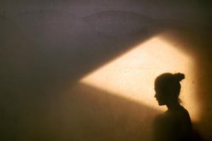 A woman sits alone in a dark room.