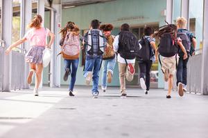 Elementary school kids run down the hallway at school.